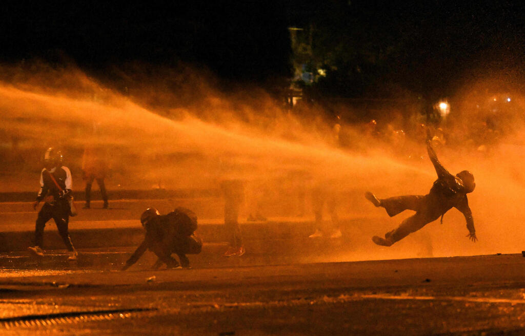 תמונות השנה של AFP שנת 2021 מפגינים סופגים זרנוקי מים בהפגנות נגד נשיא קולומביה בוגוטה 12 יוני