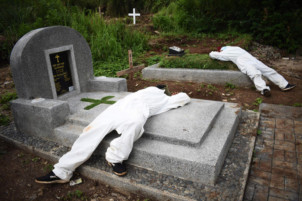 תמונות השנה של AFP שנת 2021 חופרי קברים מותשים נחים בהפסקה ב בית קברות ל חולי קורונה בנדונג אינדונזיה 15 יוני