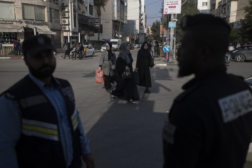 Palestinian women walk by two Hamas policemen in Gaza City 