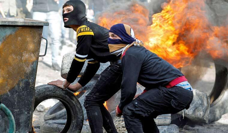 Palestinian demonstrators stand by a burning barricade during a protest against Jewish settlements, in Burqa village, in the Israeli-occupied West Bank December 24, 2021 | Reuters