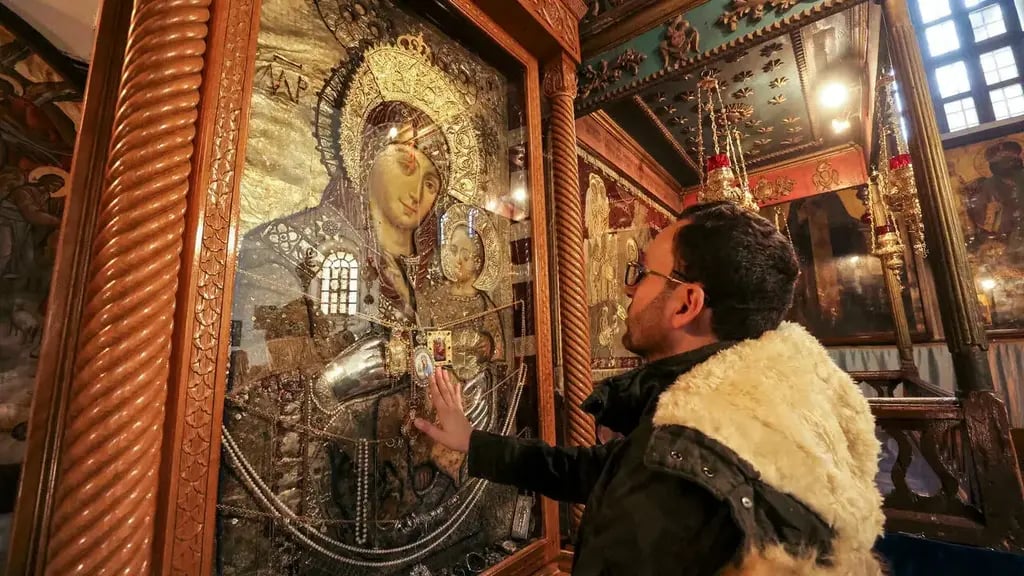 Milad Ayyad, a Palestinian Greek Orthodox Christian from Gaza, touches the icon of the Virgin and Child for a blessing at the Greek Basilica at the Church of the Nativity