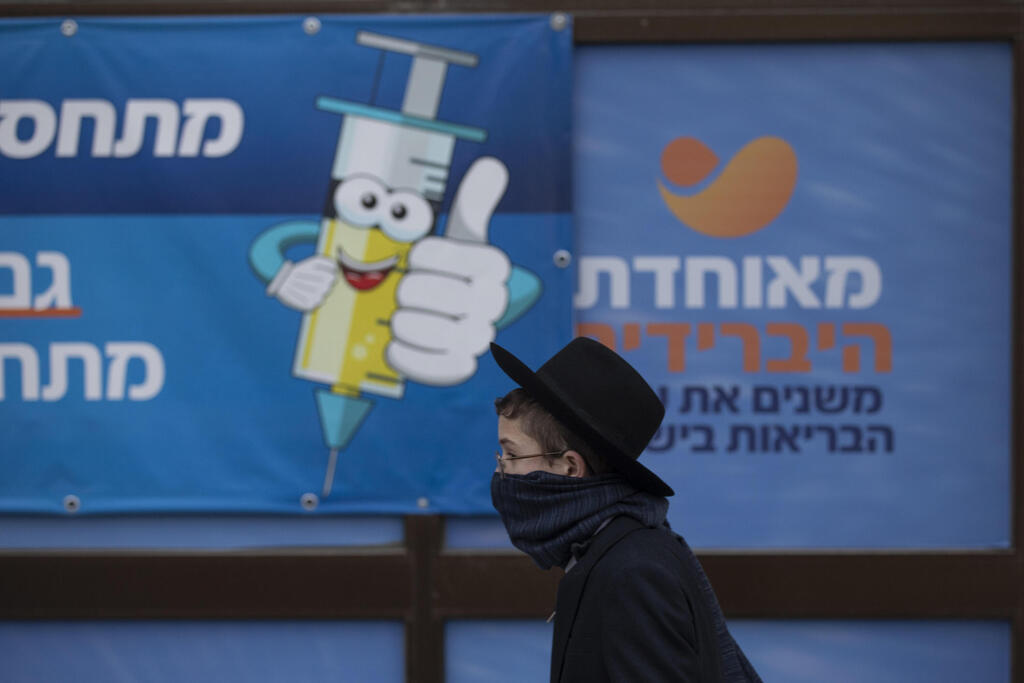 An Orthodox boy walks by a sign urging the public to get vaccinated, in Jerusalem 