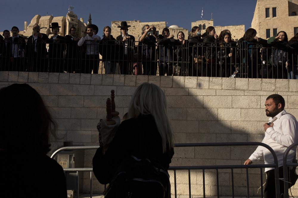 Ultra-Orthodox Jews and others watch a member of Women of the Wall carry a Torah scroll 