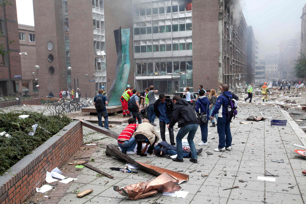 People taking care of a victim of bomb planted by Breivik that rocked the Norwegian capital of Oslo, July 22, 2011 