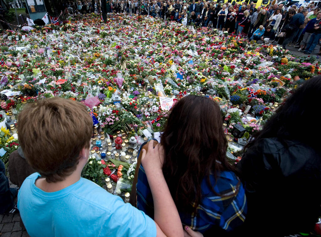 People gathering around a makeshift memorial outside the Domkirken church in Oslo, during commemorations for the victims of the July 22, 2011 twin attacks on government buildings and the massacre on the youth camp of the Norwegian Labour Party on the island of Utoya, July 25, 2011