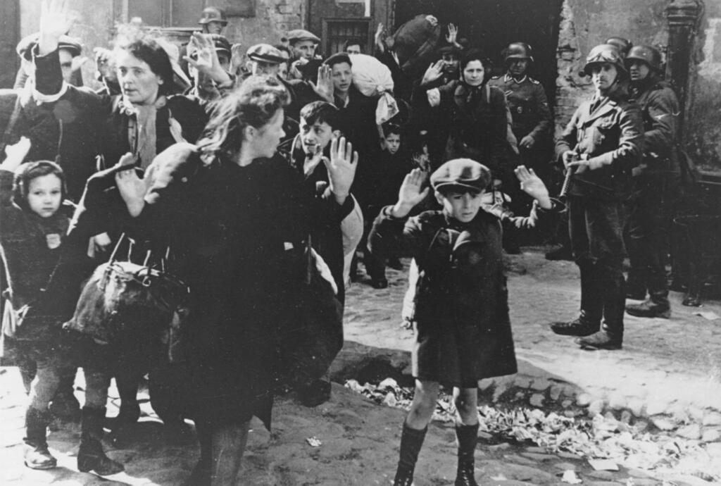 Jews, including a small boy, is escorted from the Warsaw Ghetto by German soldiers in 1943