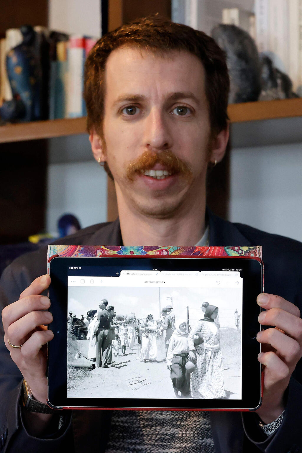 Adam Raz, an Israeli historian who works at Akevot, an organisation that specialises in state archives, displays an old picture of Palestinians