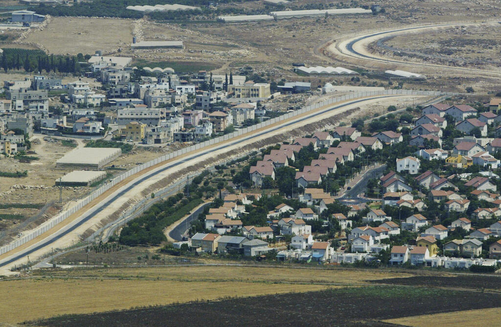 Aerial view shows a Palestinian village, left, and a settlement, right, separated by the partition wall on the West Bank 
