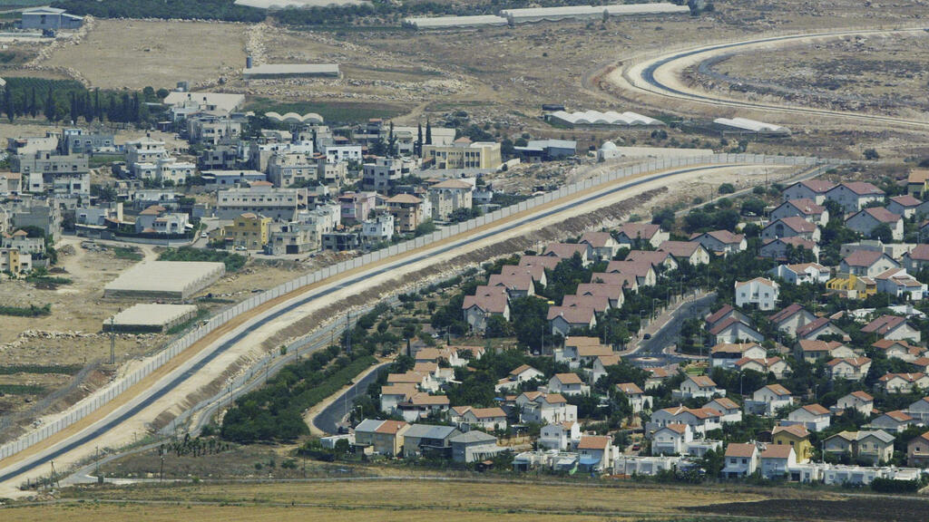 Aerial view shows a Palestinian village, left, and a settlement, right, separated by the partition wall on the West Bank 