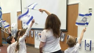 ילדים ישראלים עם דגלי ישראל במופע לקהילה באנגליה כחלק מאירוע יום העצמאות המרכזי