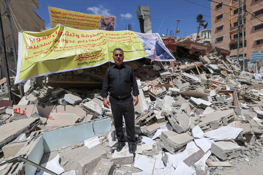 Samir Mansour stands on the rubble of his bookshop after it was destroyed in a bombing during the May 2021 fighting between Israel and the Hamas 