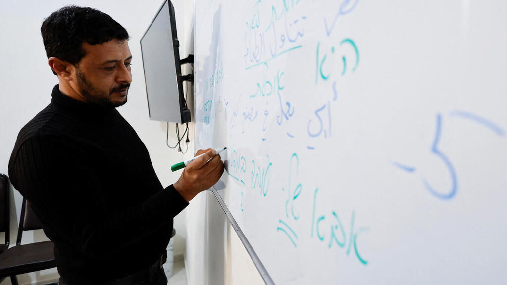 Palestinian worker Maher Al-Farra writes in Hebrew during a class at Nafha Language Center, in Khan Younis in the southern Gaza Strip 