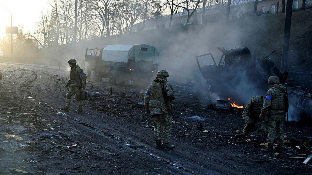 Ukrainian service members collect unexploded shells after a fighting with Russian raiding group in the Ukrainian capital of Kyiv in the morning of February 26, 2022 