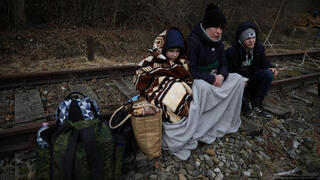 פולין פליטים אוקראינים יושבים על פסי ה רכבת  אחרי חציית הגבול ל פולין  משבר אוקראינה רוסיה מלחמה 
