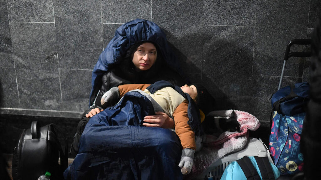 Ukrainian mother and child at the Lviv train station on Saturday (Photo: AFP) אוקראינים מחכים בתחנת הרכבת של לבוב