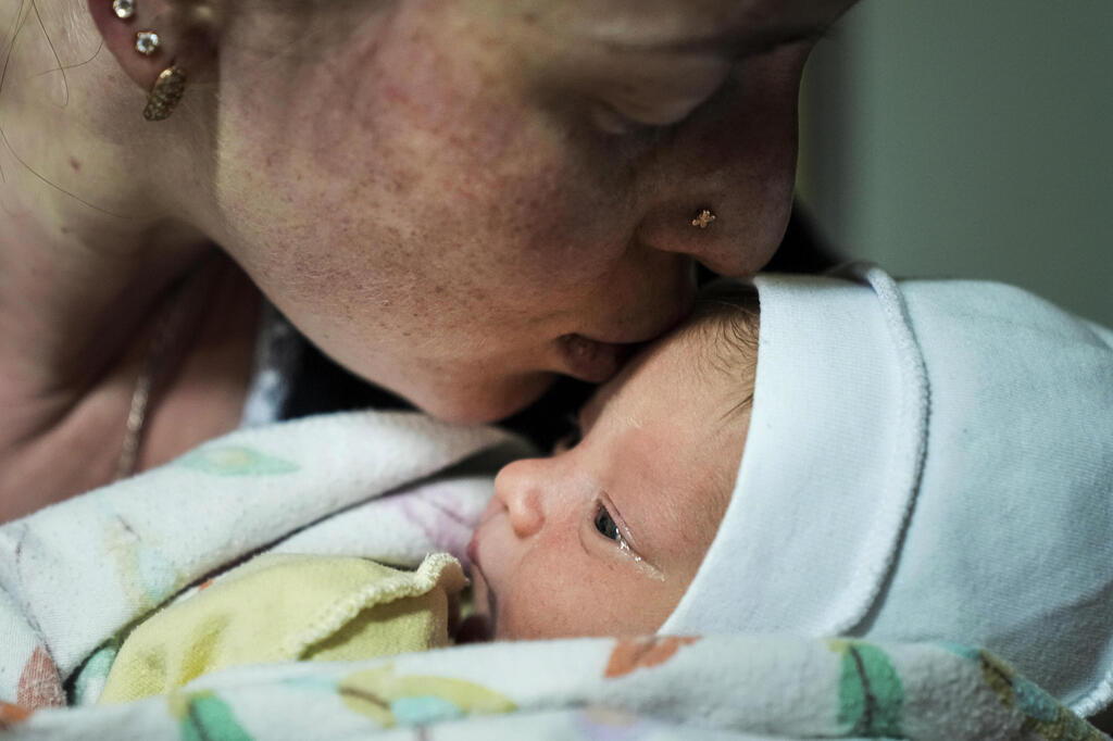 אישה מנשקת את בנה התינוק במרתף בית חולים במריופול
