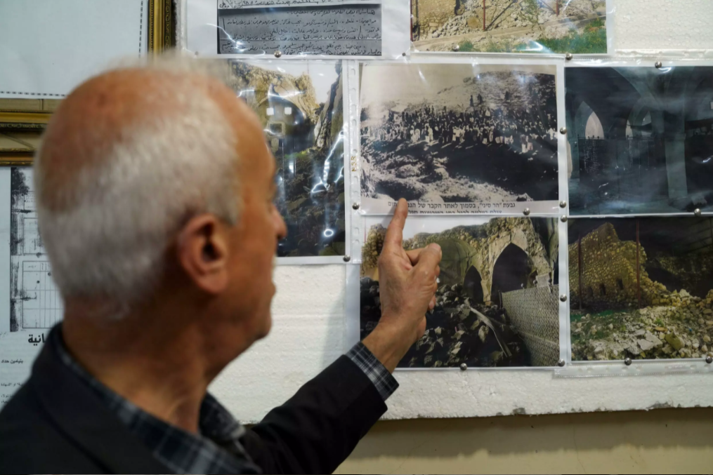 Joseph Elias Yalda, of the Al-Qosh heritage museum, points to old photographs depicting the Prophet Nahum Synagogue (Photo: AFP) Joseph Elias Yalda, of the Al-Qosh heritage museum, points to old photographs depicting the Prophet Nahum Synagogue