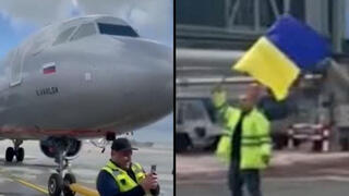 עובד ממוצא אוקראיני נעמד מול מטוס רוסי ונופף בדגל אוקראינה