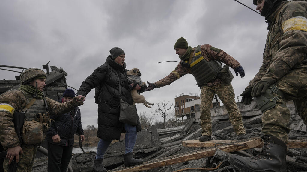 חייל חיילים של צבא אוקראינה מסייעים ל משפחה אנשים אוקראינים לחצות את נהר אירפין גשר נהרס סמוך ל קייב מלחמה עם רוסיה כלב