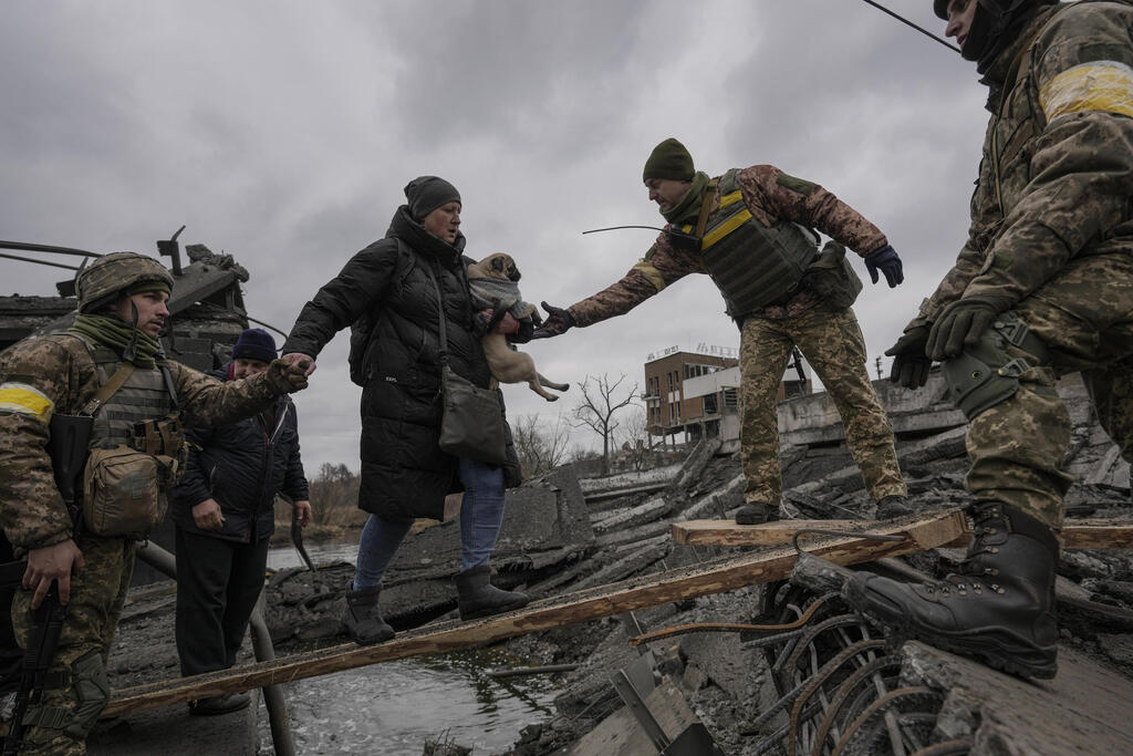חייל חיילים של צבא אוקראינה מסייעים ל משפחה אנשים אוקראינים לחצות את נהר אירפין גשר נהרס סמוך ל קייב מלחמה עם רוסיה כלב