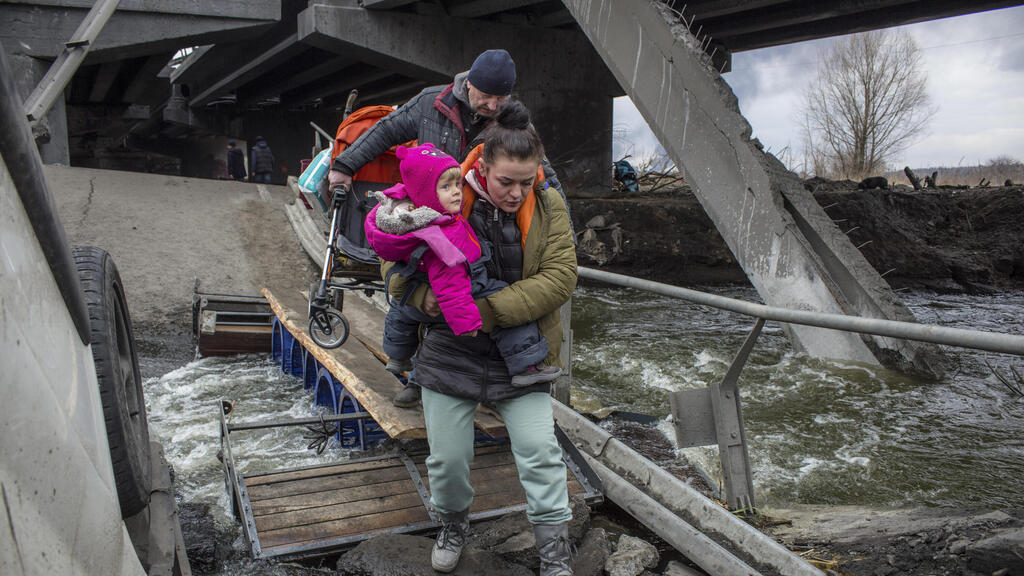 אזרחים חוצים בין הריסות גשר פגום בעיר אירפין ליד קייב