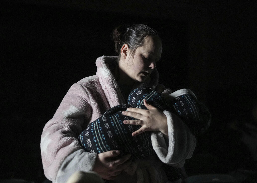 A woman holds a baby in the dark shelter in Mariupol 