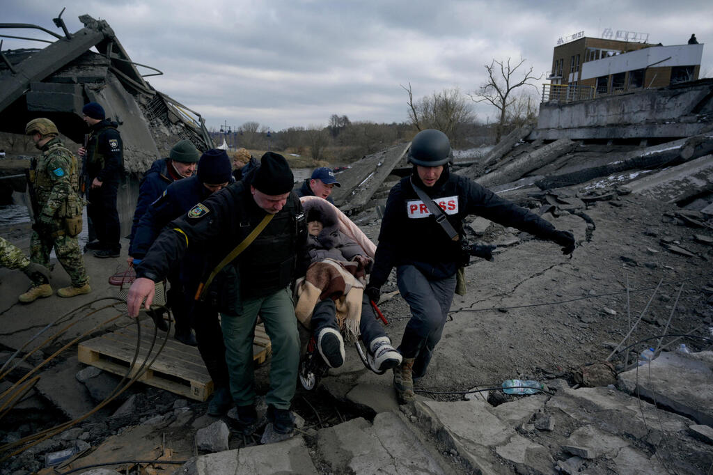 A woman is being carried over the rubble caused by Russian bombings in Irpin on Wednesday 