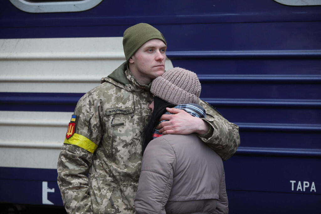 Ukrainian service member embraces partner at Lviv train station before setting out to fight Russian invaders (Photo: AFP) חיילים אוקראינים ברכבת בלבוב