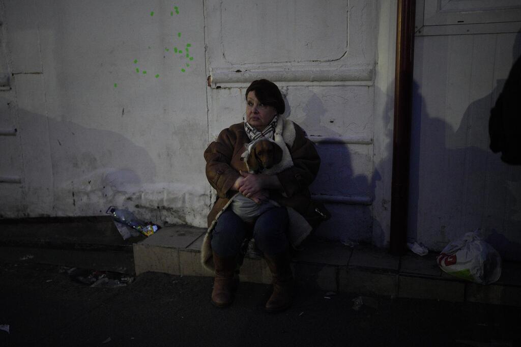 A refugee holding her dog sits by the side of the road approaching the border with Poland 