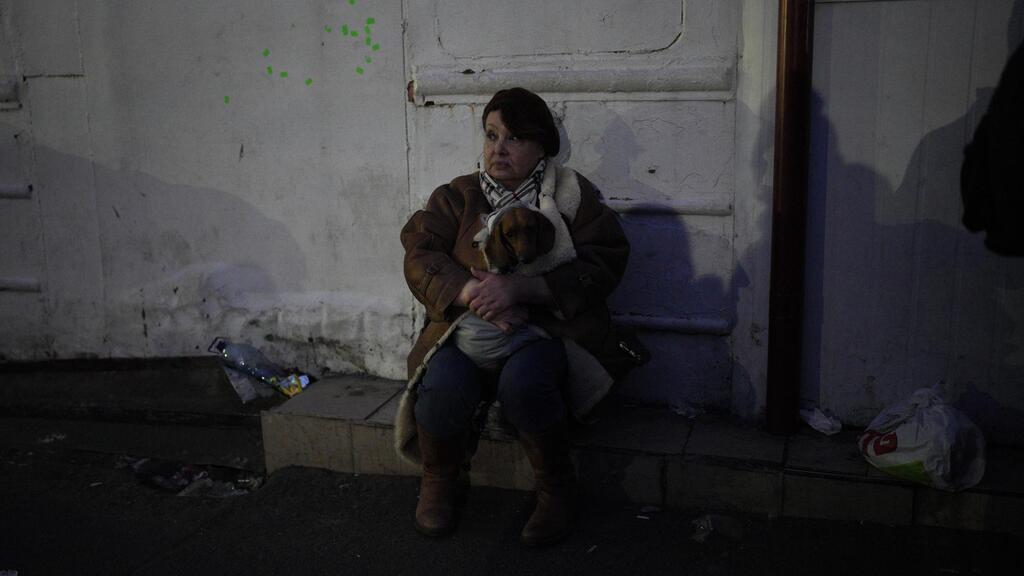 A refugee holding her dog sits by the side of the road approaching the border with Poland 