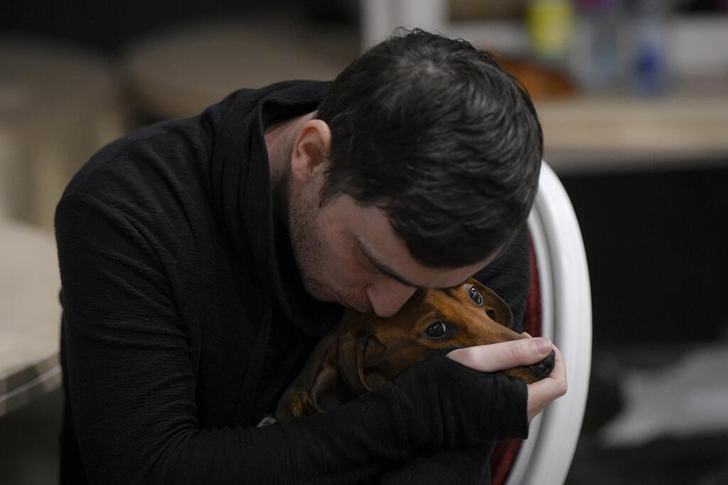 A refugee who fled the Russian invasion from neighboring Ukraine comforts his dog 