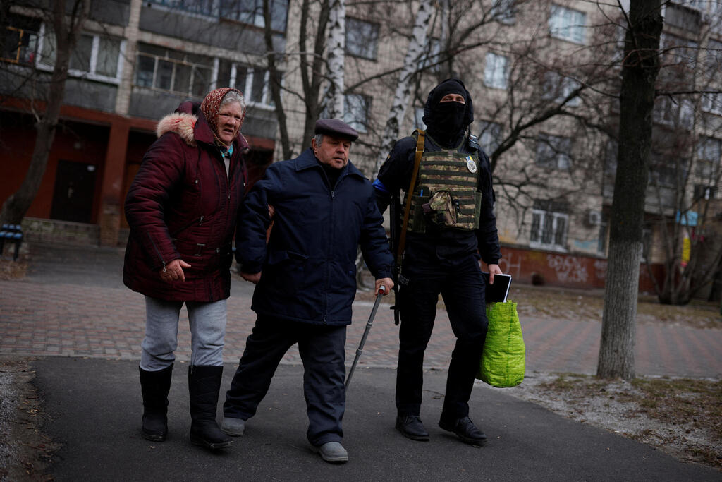 Elderly couple in Kyiv is helped to get to a bus taking civilians away from the fighting 