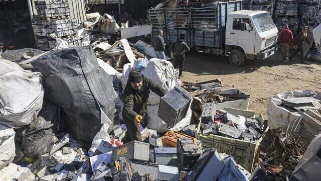 A Palestinian man picks discarded batteries to resell for recycling, at a scrapyard in Khan Yunis