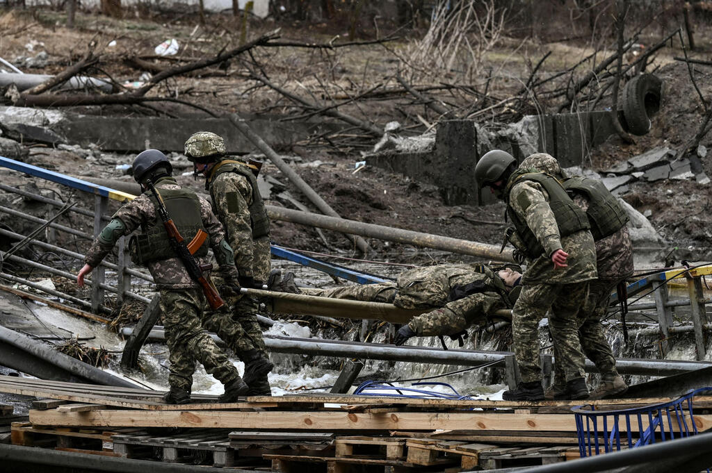 Ukrainian soldiers carry the body of a comrade killed in battle near Irpin  