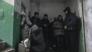 אנשים תופסים מחסה בכניסה לבניין מגורים במריופול 