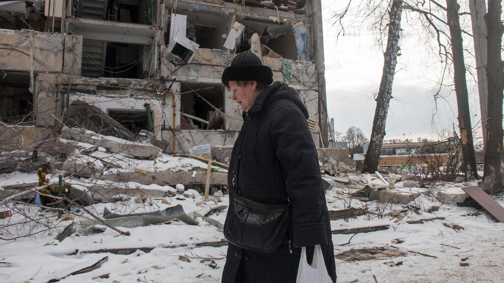 A woman walks past a bombed building in Kharkiv (Photo: AP) אישה הולכת ליד בניין שהותקף בחרקוב