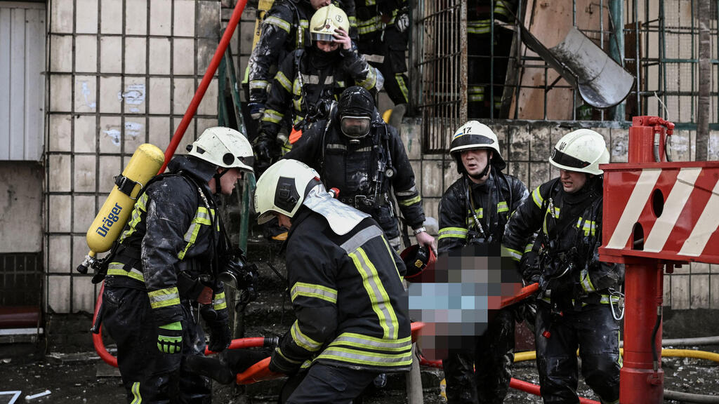 כבאים מחלצים גופת אישה ממבנה שנהרס בהפצצות על קייב 