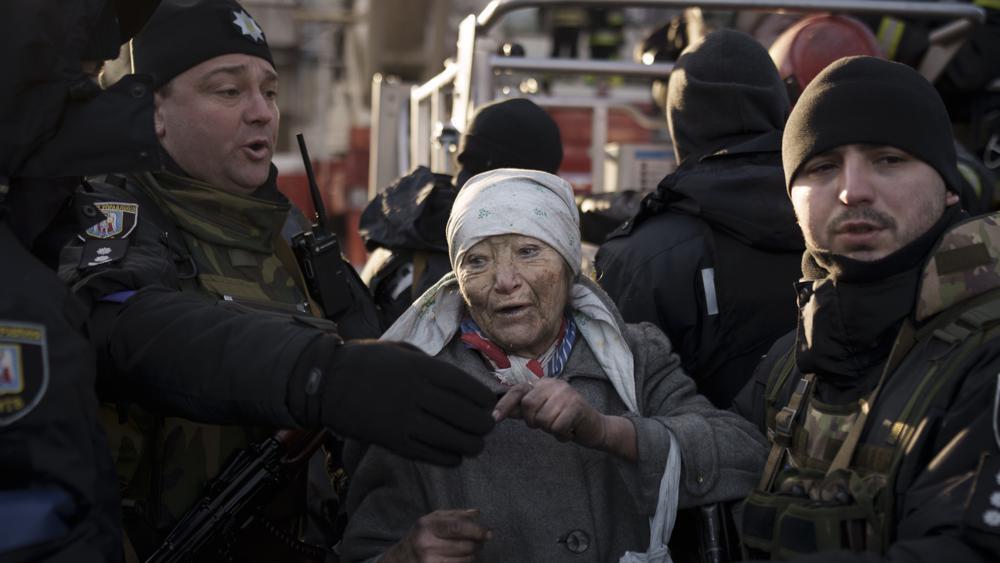 An elderly woman is helped by policemen after she was rescued by firefighters from inside her apartment after bombing in Kyiv