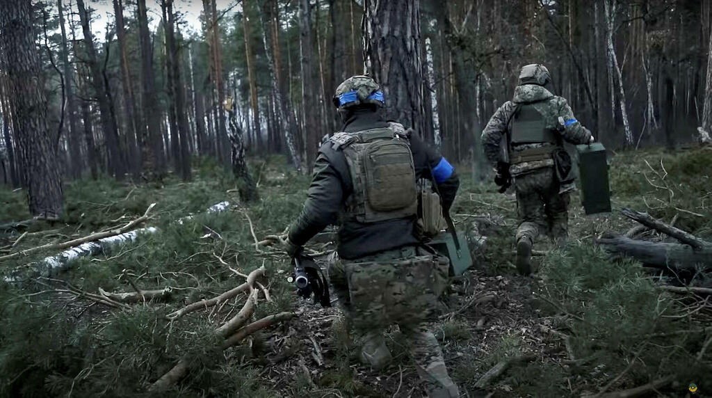 Ukrainian soldiers run through a forest, in footage said to show combat with Russian troops near the Kyiv 