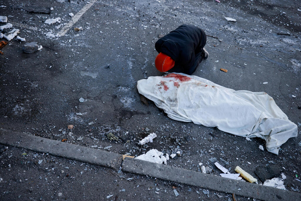 Man kneels alongside the body of his mother killed in Russian bombing in Kyiv 