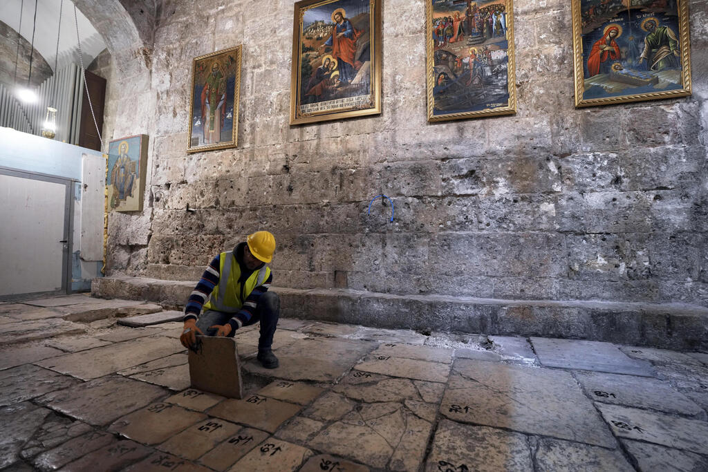 A member of the restoration team removes a stone from the floor of the Church of the Holy Sepulcher, in the Old City of Jerusalem, March 17, 2022