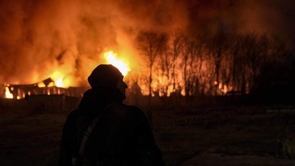 חייל אוקראיני ליד שריפה להבות אש עשן ב מחסן לאחר הפגזות תקיפות בפאתי קייב אוקראינה מלחמה באירופה משבר רוסיה פלישה
