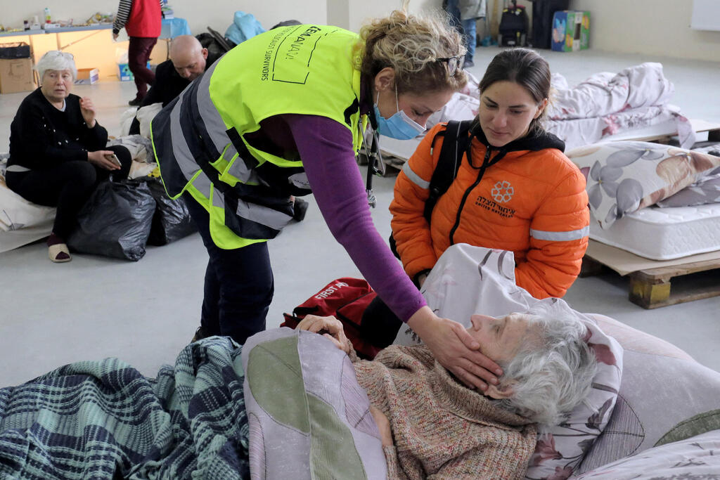 An Israeli doctor treats an elderly woman lying at a hangar complex, where Ukrainian Jewish refugees who fled the war in their country are taking refuge, in Moldova's capital Chisinau, March 13, 2022