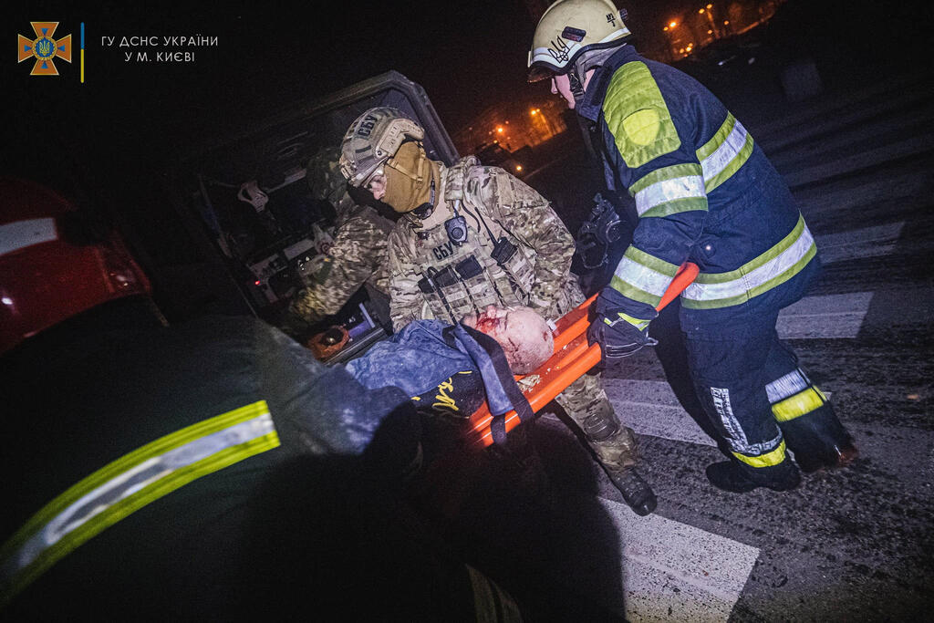 Emergency teams evacuate a wounded Ukrainian after Russian bombing of Kyiv late on Sunday 