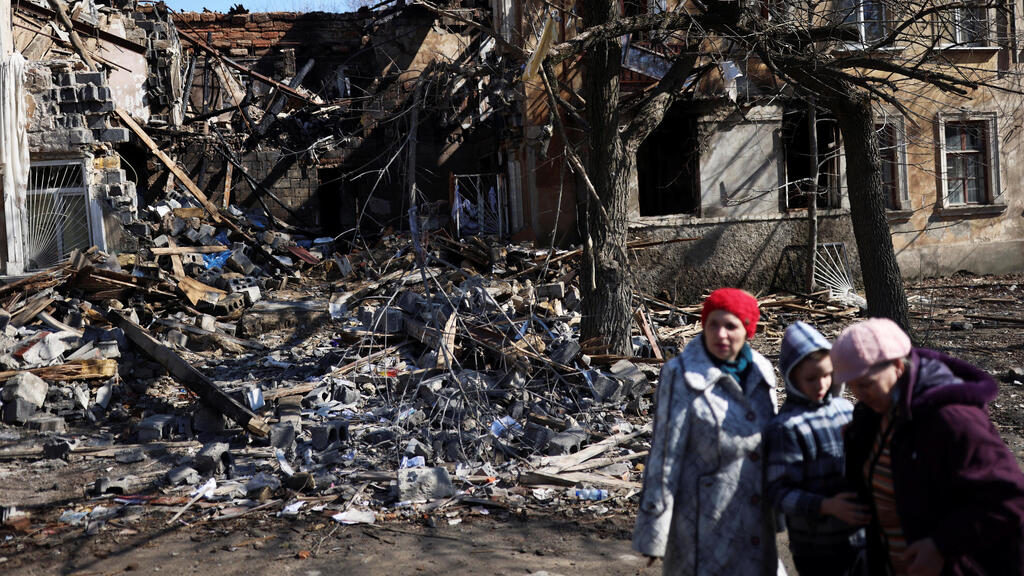 A family stands outside their home destroyed by Russian bombing in Mykolaiv on Thursday 