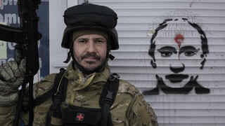 חייל אוקראיני לצד גרפיטי עם תמונת פוטין שרוף ב סטויאנקה מערבית ל קייב אוקראינה מלחמה