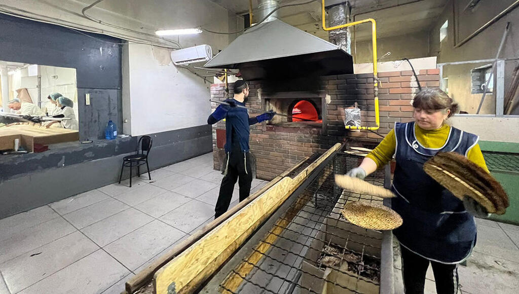 A factory worker makes shmura matzah under supervision in Ukraine