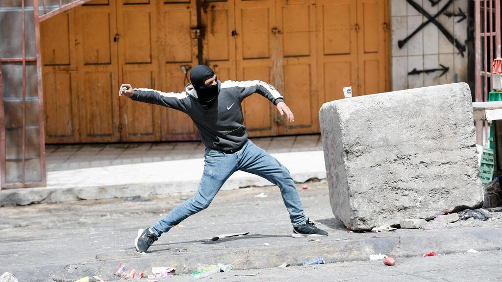 Palestinian throws a rock during riots in Hebron (Photo: Reuters) מחבל נהרג בעימותים בין פלסטינים לכוחות הביטחון צה"ל חברון
