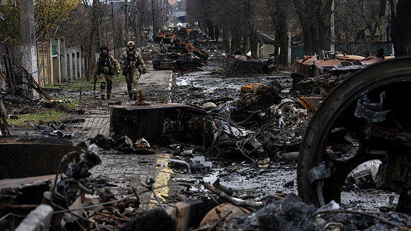 חיילים של צבא אוקראינה ליד שרידי טנקים רוסיים בעיירה בוצ'ה