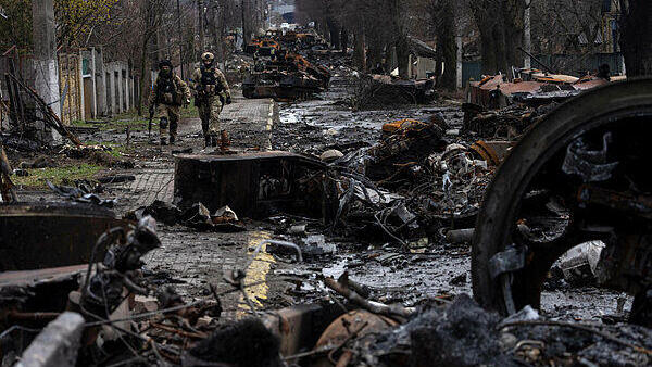 חיילים של צבא אוקראינה ליד שרידי טנקים רוסיים בעיירה בוצ'ה